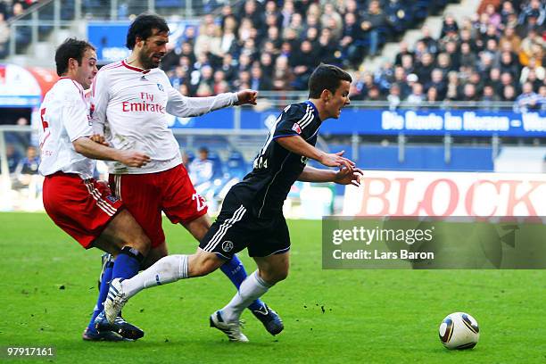 Joris Mathijsen and Ruud van Nistelrooy of Hamburg challenge Alexander Baumjohann of Schalke in the penalty box during the Bundesliga match between...