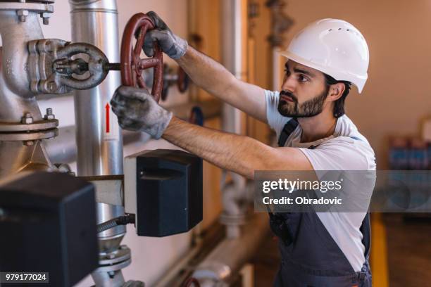 worker with helmet in front of pipes with valves - obradovic stock pictures, royalty-free photos & images