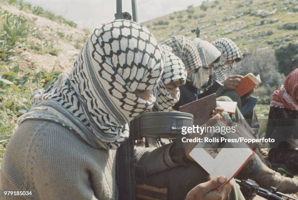 Armed Palestinian fighters of the Fatah faction of the Palestine Liberation Organisation pictured reading copies of Quotations from Chairman Mao...