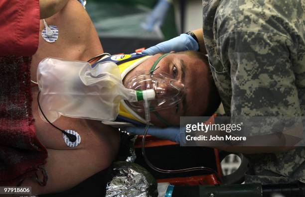British Army Lcpl. Daniel Herschell is turned on his side as doctors check his back at the Role III Multinational Medical Unit on March 21, 2010 at...