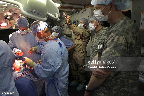 Navy Chaplain LCDR. Charles Hodges photographs as doctors perform brain surgery on an Afghan civilian on March 21, 2010 at the military hospital at...