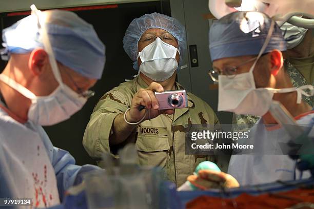 Navy Chaplain LCDR. Charles Hodges photographs as doctors perform brain surgery on an Afghan civilian on March 21, 2010 at the military hospital at...