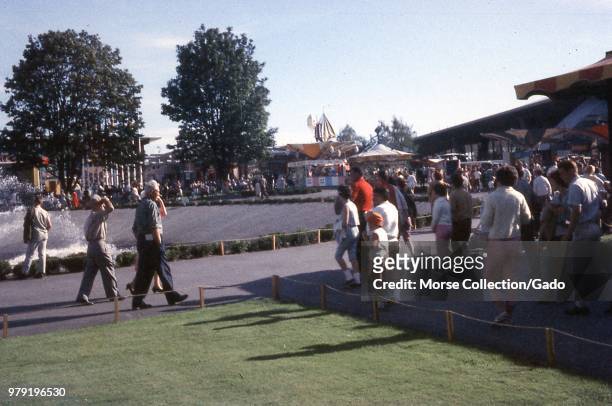 View of visitors walking next to the edge of the International Fountain at the Century 21 Expo Seattle World's Fair, in Seattle, Washington, July,...