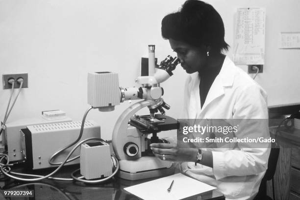 Microbiologist analyzing sera by indirect antibody staining for antibody to Legionella spp bacteria, 1950. Image courtesy Centers for Disease Control...