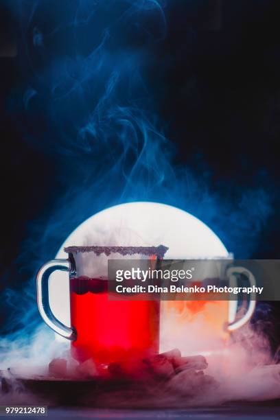 steaming hot cup of tea with berries and sugar rim. two transparent glass mugs in a backlight with rising vapor. - khabarovsk krai stockfoto's en -beelden