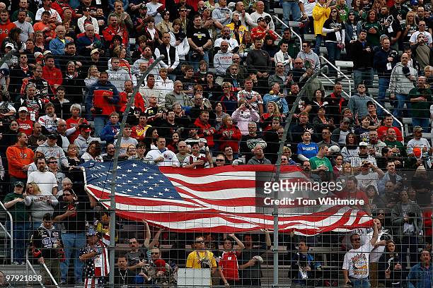 Fans hold up the American Flag during the national anthem prior to the start of the NASCAR Sprint Cup Series Food City 500 at Bristol Motor Speedway...
