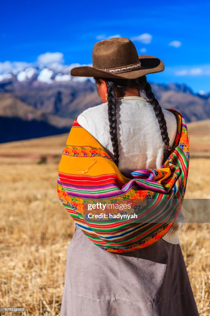 Mulher em roupas nacional peruano atravessar o campo, o Vale Sagrado