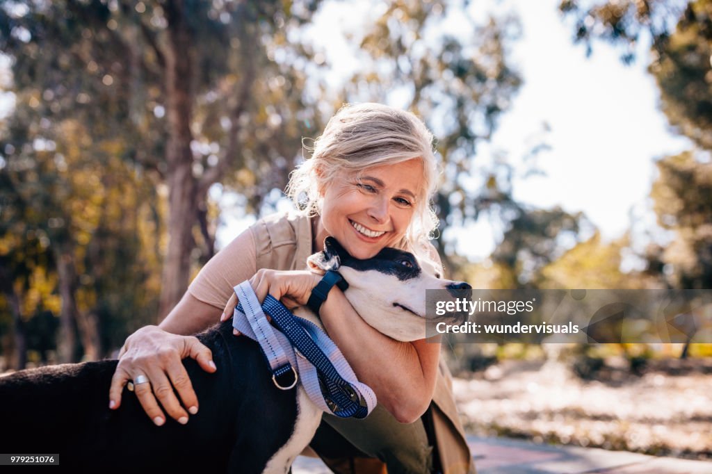 Mujer madura cariñosa abrazar mascota perro en la naturaleza