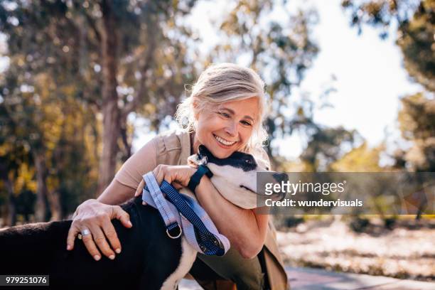 mujer madura cariñosa abrazar mascota perro en la naturaleza - perro fotografías e imágenes de stock
