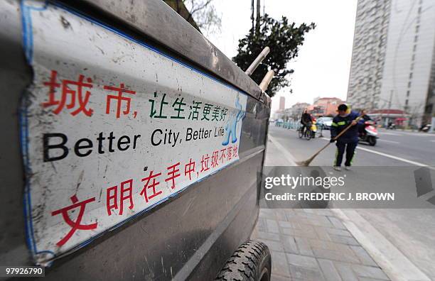 Streetsweeper sweeps the street beside her portable rubbish bin in Shanghai on March 22, 2010. China is trumpeting the World Expo, which begins on...