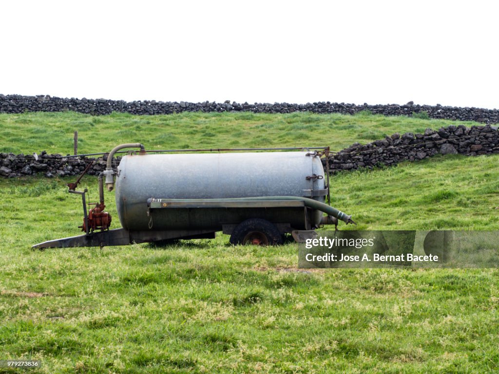 Pastoral landscape, tank metallic to drink the cattle over pastures green separated by stone walls. Terceira Island in the Azores Islands, Portugal.