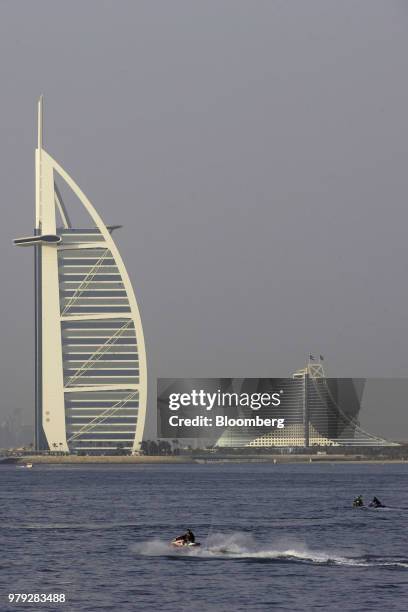 Jet skiers pass the Burj Al-Arab hotel, left, and Jumeirah Beach Hotel in Dubai, United Arab Emirates, on Friday, June 15, 2018. Since the 1970s,...