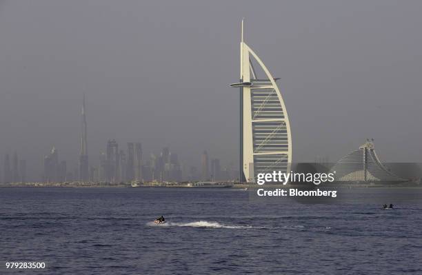 Jet skiers pass the Burj Al-Arab hotel, second right, and Jumeirah Beach Hotel, right, in Dubai, United Arab Emirates, on Friday, June 15, 2018....