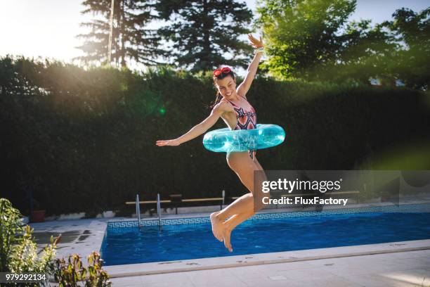 cheerful girl in a swimsuit jumping buy the pool - jumping in pool stock pictures, royalty-free photos & images