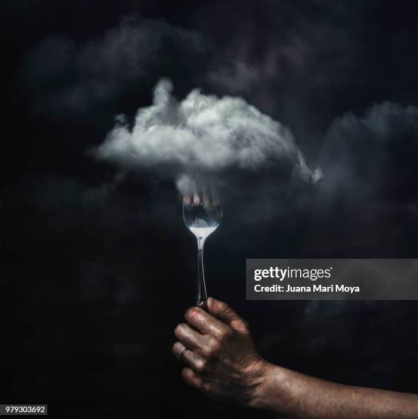 the taste of the clouds. hand by clicking a cloud in the sky, with a fork . conceptual photography - rebirth stock-fotos und bilder