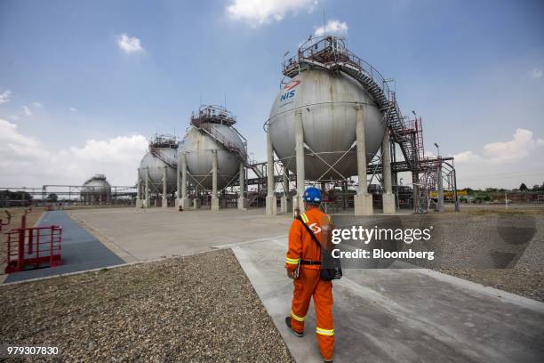 Worker walks towards liquid petroleum gas storage tanks at the Naftna Industrija Srbija AD oil refinery, operated by OAO Gazprom Neft PJSC, in...