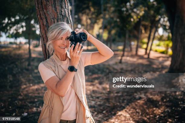 gelukkig modieuze volwassen vrouw met smartwatch en camera in park - wearable camera stockfoto's en -beelden