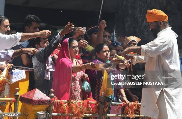 Indian Kashmiri Pandits offer alms at the Mata Kheer Bhawani Temple during its annual festival in the village of Tullamulla, some 20 kms from...