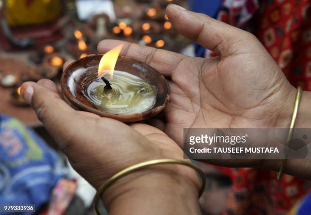 Kashmiri Pandit offers prayers while holding earthen lamps at the Mata Kheer Bhawani Temple during its annual festival in the village of Tullamulla,...