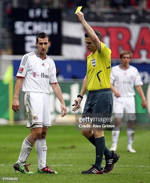 Referee Michael Weiner shows the yellow card to Miroslav Klose of Muenchen during the Bundesliga match between Eintracht Frankfurt and Bayern...