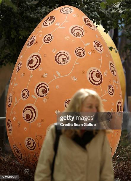 Woman walks among giant Easter eggs coloured in the numerical progression of colours within the colour spectrum at the Arkaden shopping mall on March...