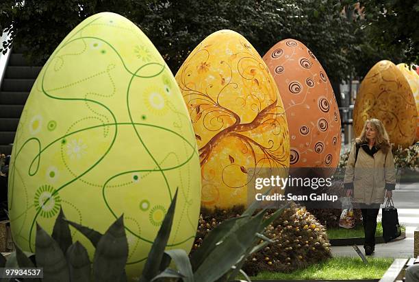 Woman walks among giant Easter eggs coloured in the numerical progression of colours within the colour spectrum at the Arkaden shopping mall on March...