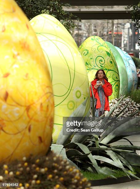 Woman walks among giant Easter eggs coloured in the numerical progression of colours within the colour spectrum at the Arkaden shopping mall on March...