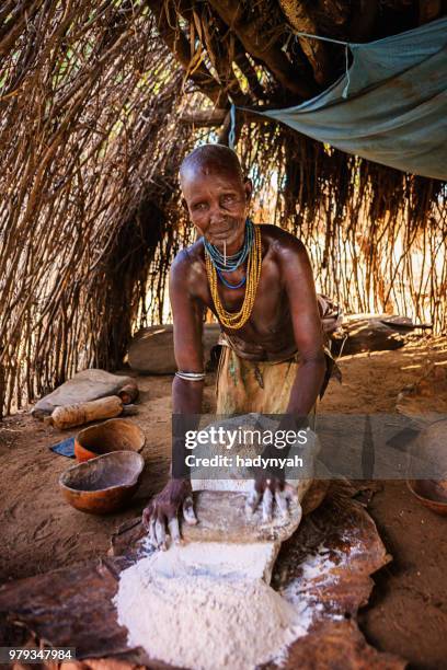 woman from karo tribe making sorghum flour, ethiopia, africa - omo valley stock pictures, royalty-free photos & images