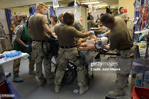 Army Spc. Benjamin McCune is turned on his side as medical personel check him for wounds at the military hospital on March 22, 2010 at Kandahar...