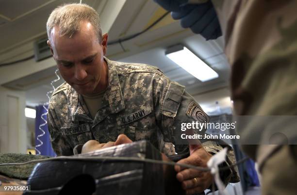 Army Chaplain CPT. Loren Aderhold prays over a wounded American soldier at the military hospital on March 22, 2010 at Kandahar Airfield, Afghanistan....