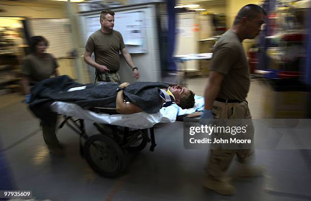 Army Spc. Benjamin McCune is carried through the trauma center after arriving to a military hospital on March 22, 2010 at Kandahar Airfield,...