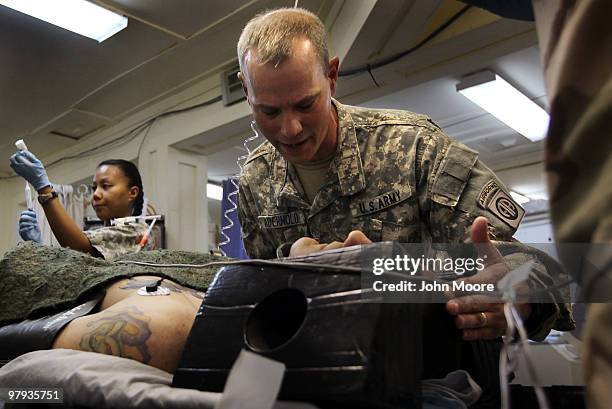 Army Chaplain CPT. Loren Aderhold prays over a wounded American soldier at the military hospital on March 22, 2010 at Kandahar Airfield, Afghanistan....