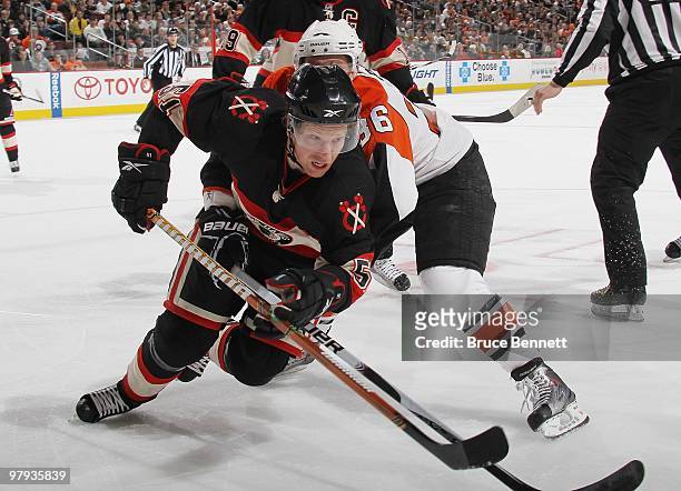 Brian Campbell of the Chicago Blackhawks moves around Darroll Powe of the Philadelphia Flyers at the Wachovia Center on March 13, 2010 in...