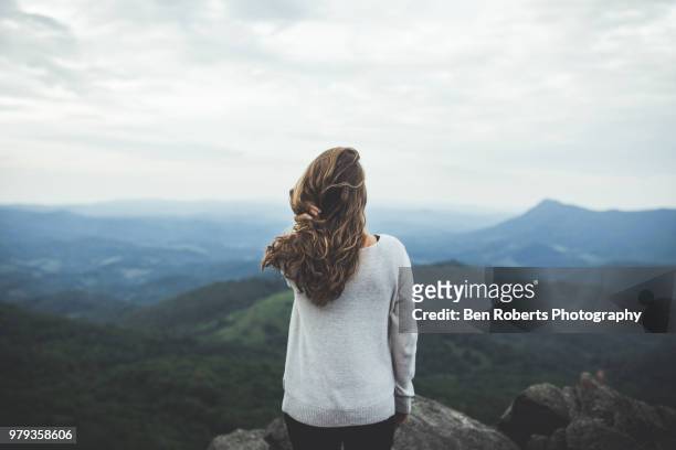woman stares out at a beautiful mountain scene - fashion for peace stockfoto's en -beelden