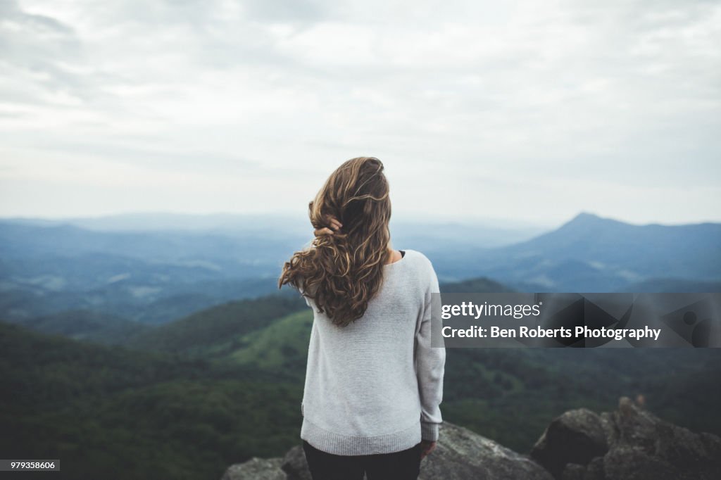 Woman stares out at a beautiful mountain scene
