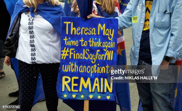 Pro-EU supporters hold placards during an anti-Brexit demonstration outside the Houses of Parliament in London on June 20, 2018. - British Prime...