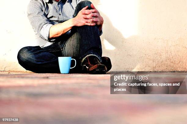 a guy sitting againt the wall with a blue cup - againt stock pictures, royalty-free photos & images