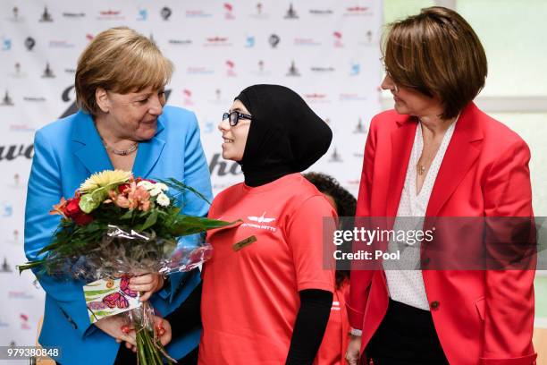 German Chancellor Angela Merkel talks to a young member of the sports club 'SV Rot-Weiss Viktoria Mitte 08', Joudi , who presented her with some...