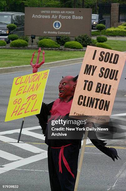 Protestor dressed as a devil carries a sign outside Andrews Air Force Base in Maryland, denouncing the INS raid that took Elian Gonzalez from his...