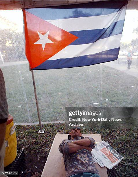 Protestor lies under Cuban flag during demonstration outside the Federal Building in Miami against the Immigration and Naturalization Service's...