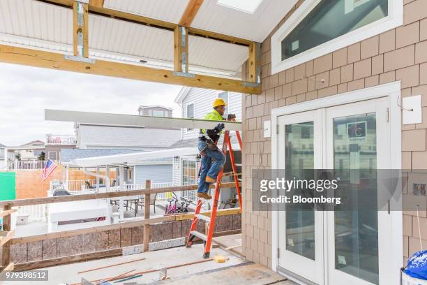 Worker climbs a ladder to install a gutter during construction of a home designed to withstand extreme weather in the Breezy Point neighborhood of...
