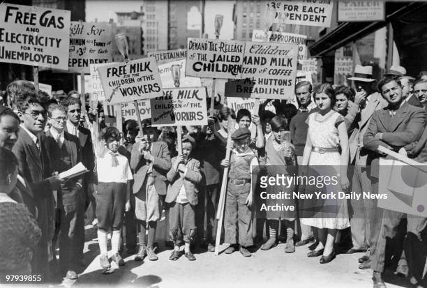 Children who are among the 10,000 communists and unemployed marching on City Hall bear signs demanding free milk for children of the unemployed.