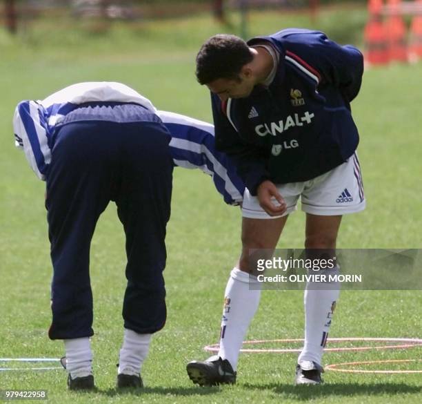 L'assistant de Roger Lemerre, Guy Stefan, examine la cuisse blessé de l'international Youri Djorkaeff, le 19 mai 2000 à Bourg-Saint-Maurice, lors...