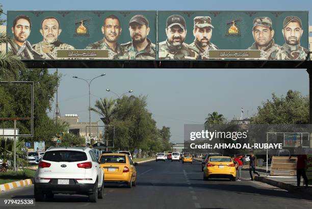Picture taken on June 20, 2018 shows a propaganda billboard for the pro-Iran Hezbollah Brigades militia hanging on a pedestrian crossing over...