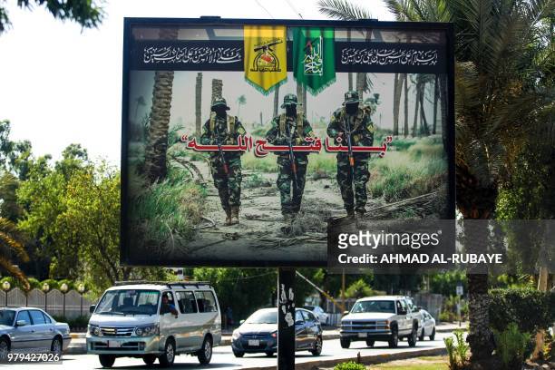Picture taken on June 20, 2018 shows a propaganda billboard for the pro-Iran Hezbollah Brigades militia hanging over Palestine Street in the centre...