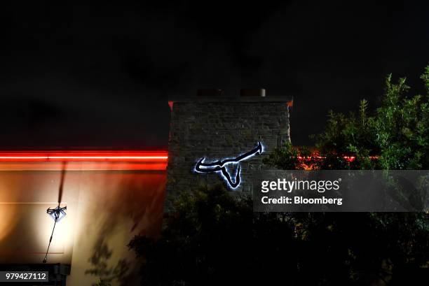 The Darden Restaurants Inc. Longhorn Steakhouse logo is seen illuminated at night outside a location in San Antonio, Texas, U.S., on Monday, June 18,...