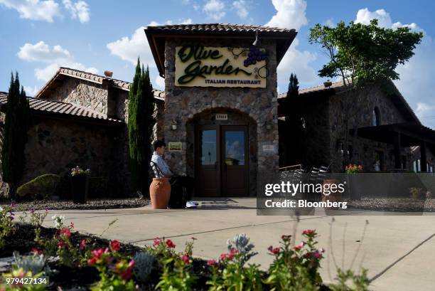 Customer sits outside a Darden Restaurants Inc. Olive Garden location in San Antonio, Texas, U.S., on Wednesday, June 13, 2018. Darden Restaurants...