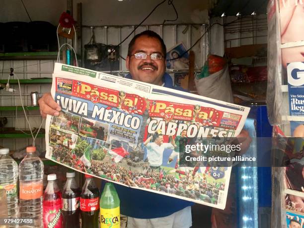 June 2018, Mexico, Mexico City: A newsagent holding up a copy of the newspaper 'Pásala' with the title 'viva mexiko cabrones' , a day after the...