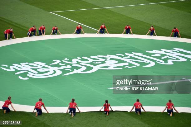Volunteers deploy Saudi Arabia's giant flag on the pitch before the start of the Russia 2018 World Cup Group A football match between Uruguay and...
