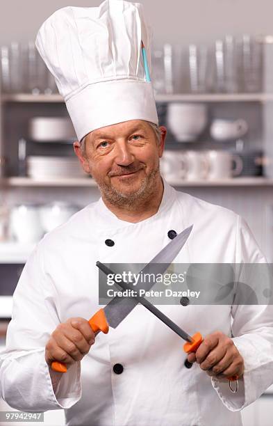 senior chef sharpening knife in kitchen - carvery stockfoto's en -beelden